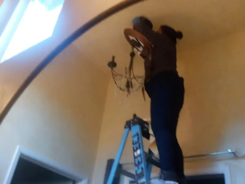 Electrician installing a chandelier in a Midway residence